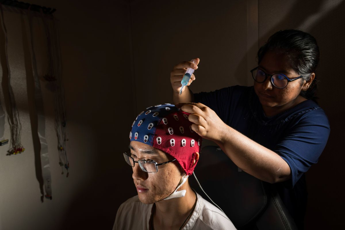 生物医学工程专业的高年级学生索菲娅·乌尔比·比斯瓦斯正在给同事金豆戴上脑电图帽, 生物医学工程的博士生.